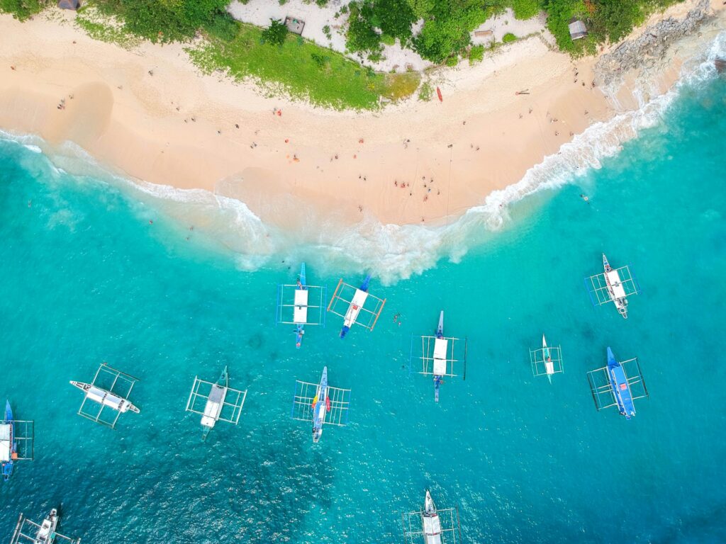 aerial view of boats, white sand beach and crytal clear waters in Helicopter Island El Nido Palawan Philippines