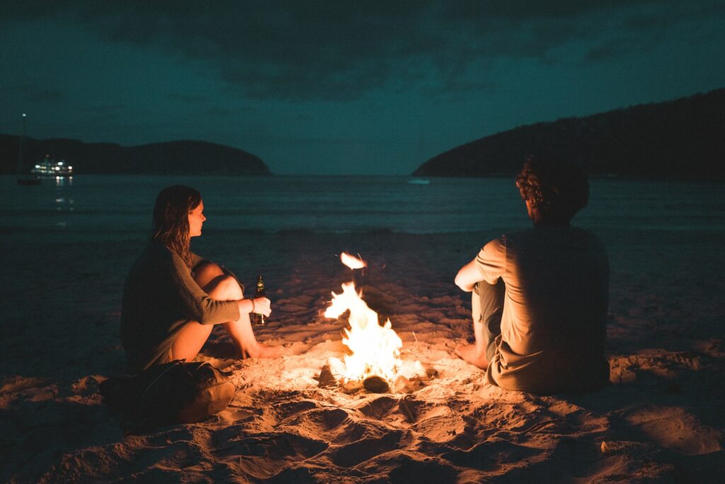 Couple chilling by the beach bonfire