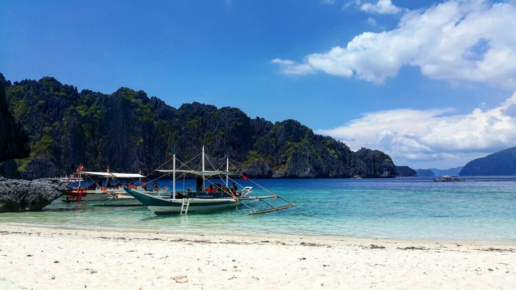 two small island hopping boats resting on the beach front