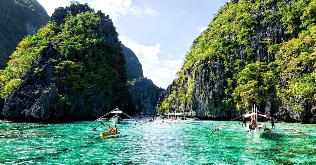 tourists kayaking in the crystal waters of Big Lagoon in El Nido, Palawan, Philippines