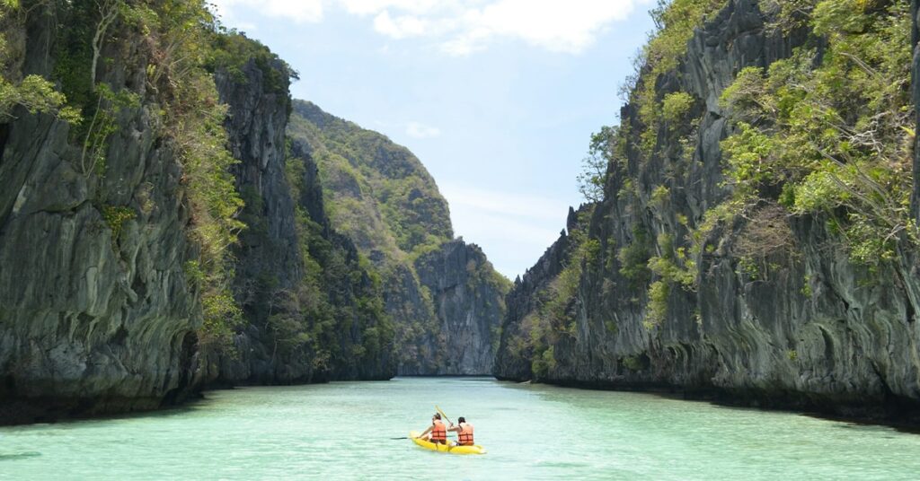 tourist kayaking in clear waters of Big Lagoon in El Nido, Palawan, Philippines