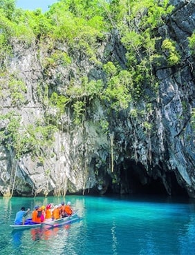 Tourists entering Puerto Princesa Subterranean River National Park in Palawan, Philippines, surrounded by lush vegetation and limestone cliffs, ready for a boat tour