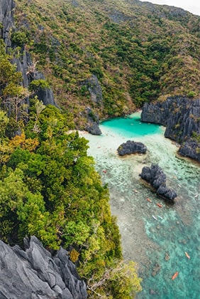 Secret Beach in El Nido, Palawan, Philippines featuring a hidden cove with turquoise waters, surrounded by towering limestone cliffs and lush greenery