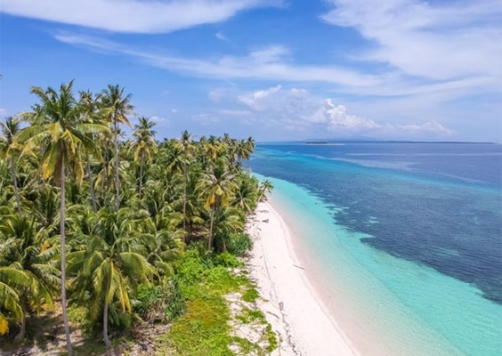 Idyllic view of Balabac Beach in Palawan, featuring soft white sand, crystal-clear turquoise waters, and lush greenery, with a serene atmosphere perfect for relaxation