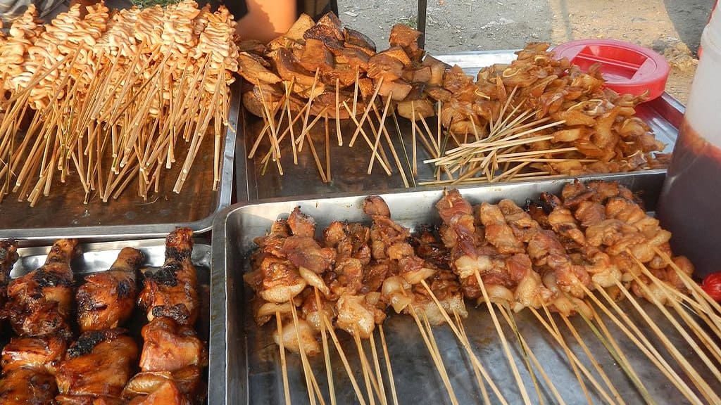 A variety of grilled street food skewers, including isaw ng manok (chicken intestines) and barbecue (pork or chicken), served at an ihaw-ihaw stall, showcasing some of the best food in El Nido, Philippines.