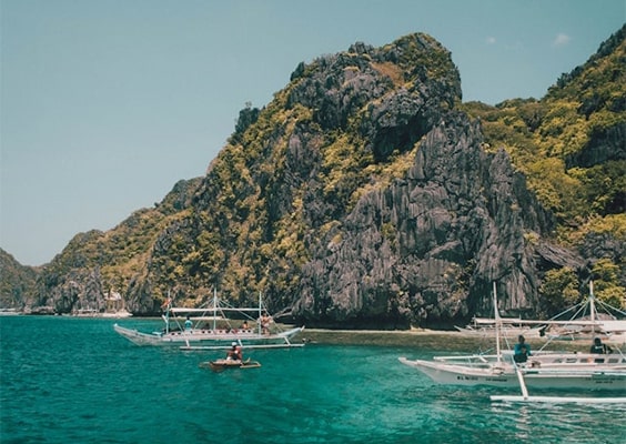 Exciting island hopping activity in Palawan, showcasing vibrant turquoise waters, lush tropical islands, and tourists exploring by boat, with snorkeling gear and beach gear visible as they enjoy the stunning scenery