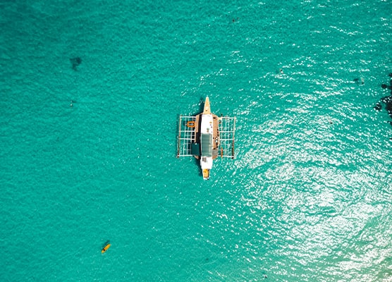 A top-down view of a boat drifting on the calm, turquoise waters of Palawan, Philippines